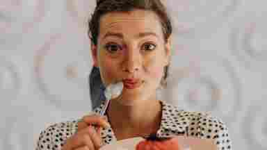 A young woman looks excited as she eats a sugary dessert.