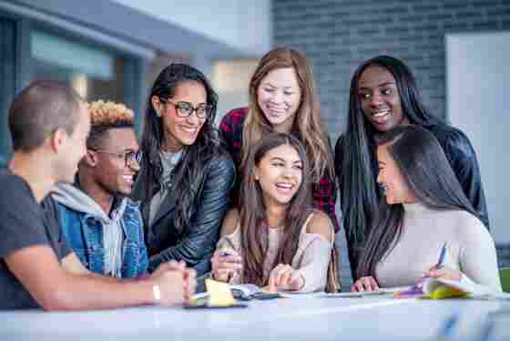 A diverse group of happy college students sitting around a table. iStock-1067477990