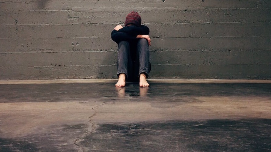a girl curled up next to a wall. 