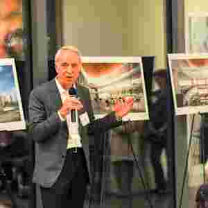 Speaker talks in front of rendered Brain Performance Institute building plans.