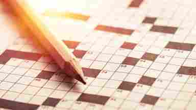 pencil laying on top of a cross word puzzle.
