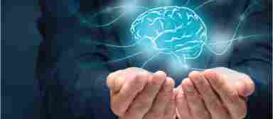 A person in business clothes holds a glowing blue brain within their hands.