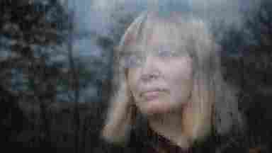 Portrait of a middle-aged woman looking through a window on a rainy day.