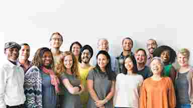 A diverse group of adults smiling into the camera.