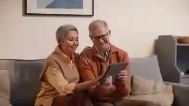 Man and a women of color looking at an Ipad on the couch