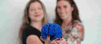 Smiling guests at a Center for BrainHealth event share a 3-D printed brain with the camera.
