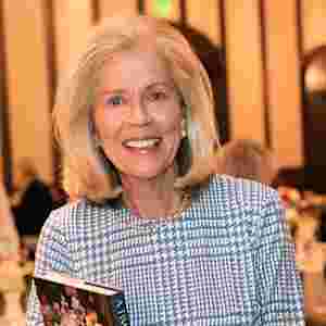 Debbie Francis, Legacy Award recipient 2008. She is wearing a blue plaid outfit with pearls and is holding a book.