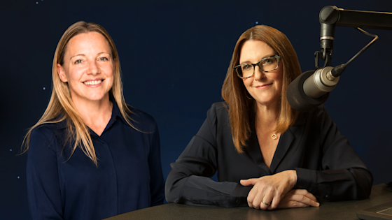 Promo photo of psychologist Alia Crum, PhD, and KERA's Krys Boyd or the 2026 season of BrainHealth Presents in Dallas, Texas, shown wearing dark tops and posing near a studio microphone against a deep blue starry background.
