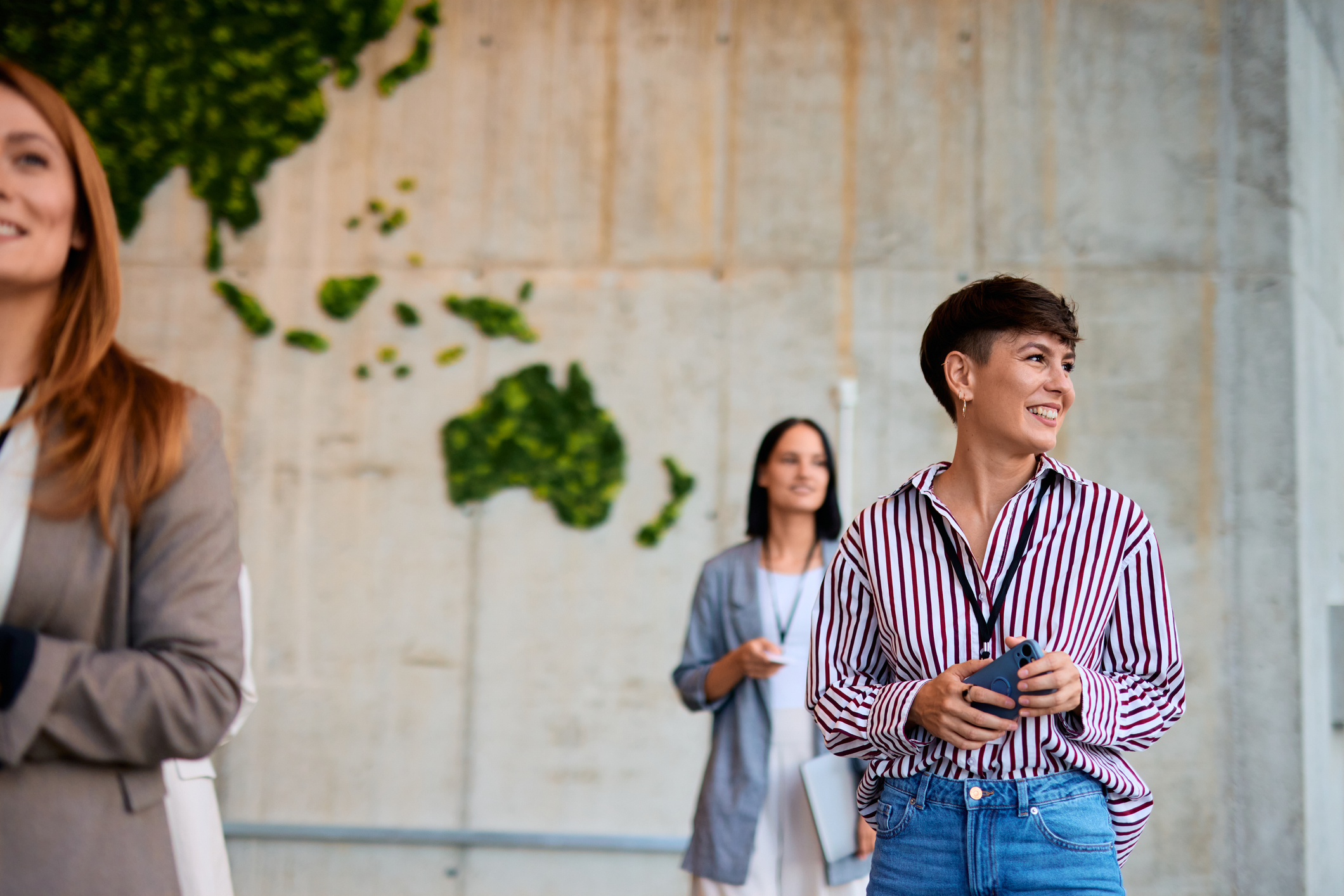 Your professionals engage with one another during a conference break, casually photographed in a well lit office space with biophilic design elements. 