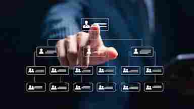A suited businessman points at a glowing digital organizational chart hierarchy displayed against a dark blue background.