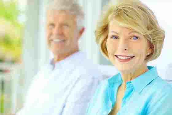 Happy elderly couple smiling, looking at the camera. Older. White.