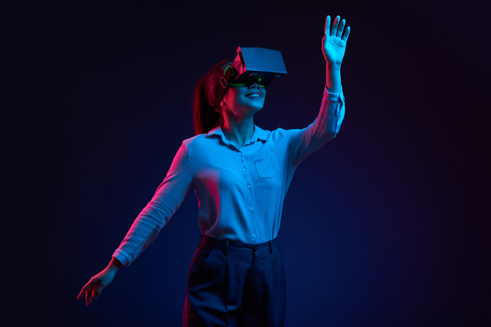 A photograph of a young woman earing VR goggles and engaged in a virtual experience.