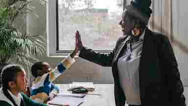 Adolescent students and teacher smiling by a window.