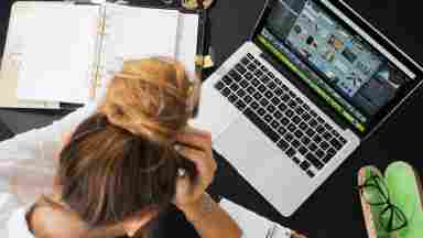 A women working at her desk surrounded by paper with her computer open