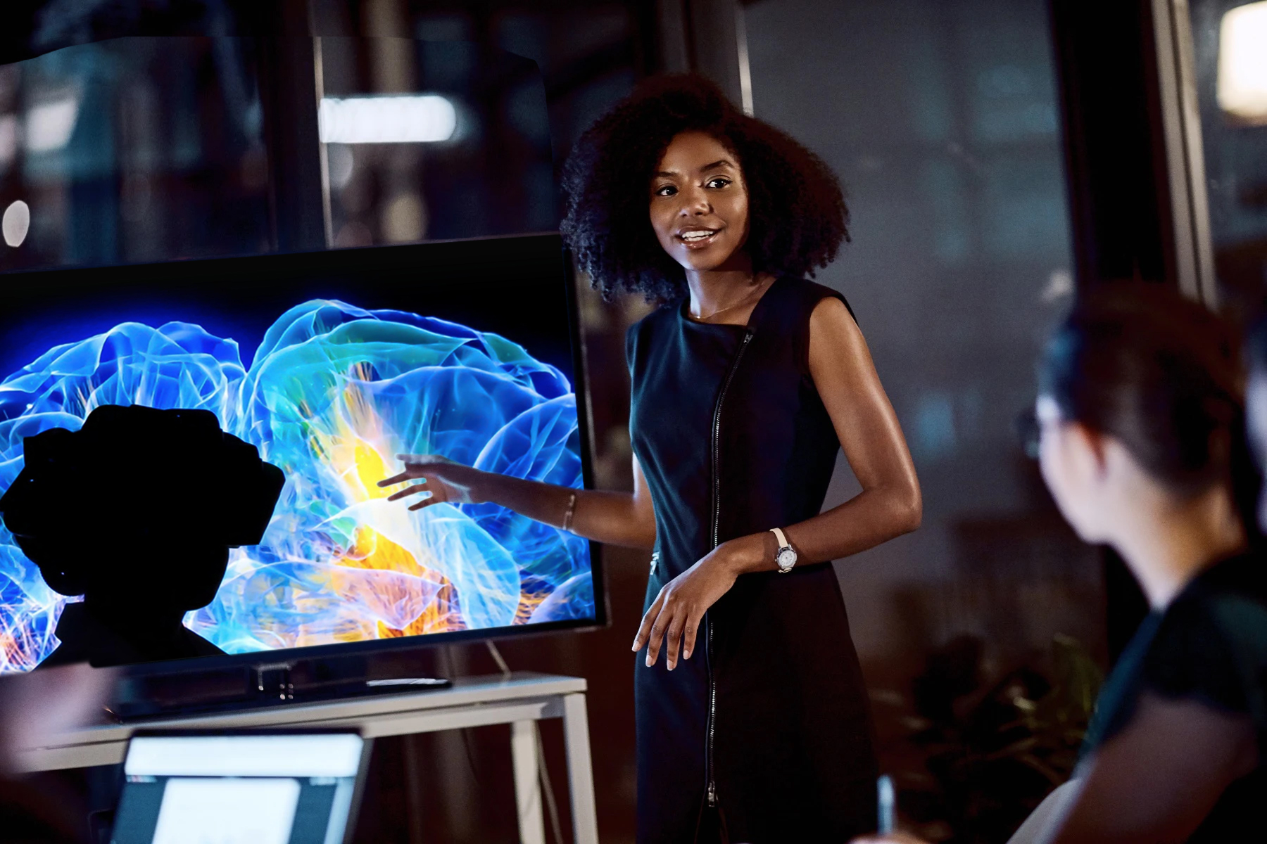 A young Black woman presents a VR simulation of the inside of the human brain. 