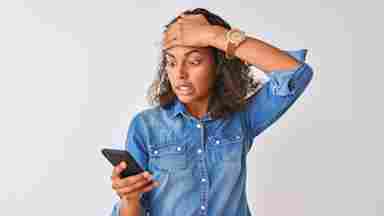 A stressed woman is looking at her phone.