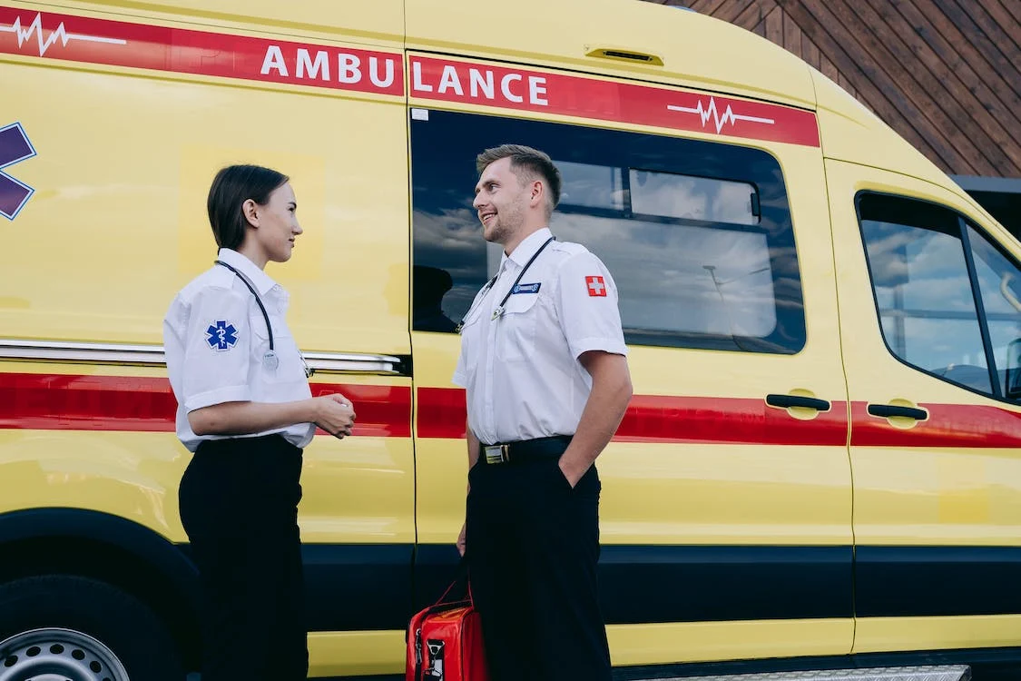A man and a women have a conversation next to an ambulance