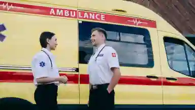 A man and a women have a conversation next to an ambulance