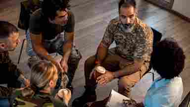 Diverse group of military servicemembers meet with as a group with support from a trained BrainHealth coach.