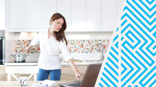 A Woman in the Kitchen Looking at the Computer Cooking; Multitasking; Distractions. IStock# 476295592.
