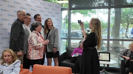 Guests at BrainHealth Presents experience the red carpet treatment in front of the Center for BrainHealth photo wall.