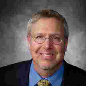 Dr. Bart Rypma is wearing a suit with gray background, horizontal- Hero. Close-up.