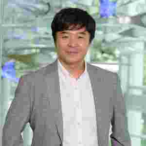 Yune S. Lee is wearing a gray blazer with blue lights, horizontal. Close-up.