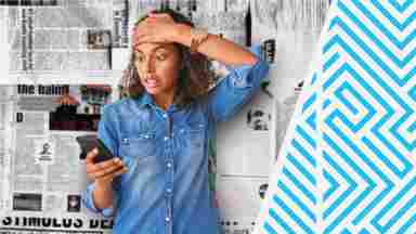 A woman holding her head and looking at her phone in exasperation.