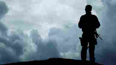 Silhouette of a soldier overlooking the cloudy horizon.