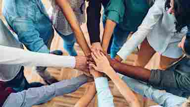 Community members bring their hands together in unity and solidarity.