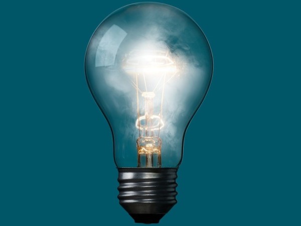 A floating light bulb that has white smoke with a teal background.