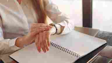 Entrepreneur checking the time while working in a journal.