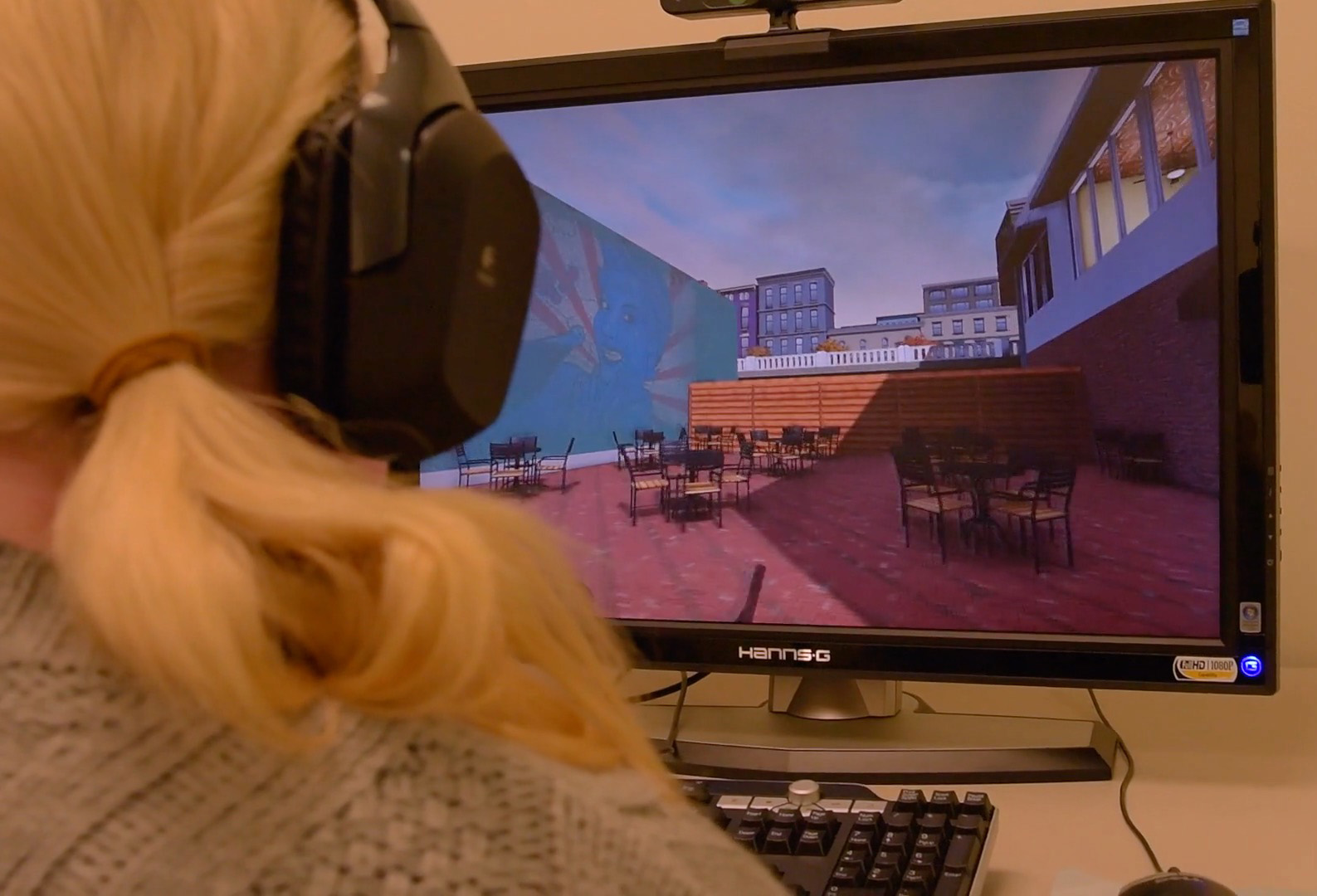 A person wearing headphones uses a computer to participate in a virtual reality training program in order to improve social skills.