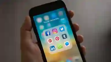 A person holding up a phone with various social media apps open. 