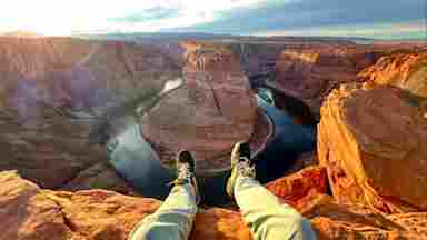 A young adult rests besides the Grand Canyon taking in the expansive perspective of the landscape.