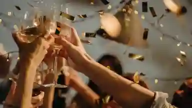 Many people raising wine glasses in cheers while there is confetti in the background