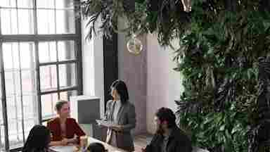 Diverse business team works in well-lit conference room created using biophilic design.