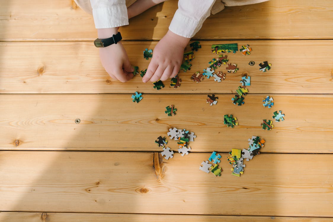 A child putting together a puzzle on a wooden floor. 