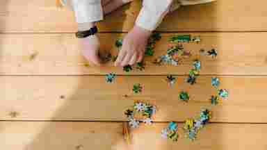 A child putting together a puzzle on a wooden floor.