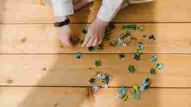 A child putting together a puzzle on a wooden floor. 