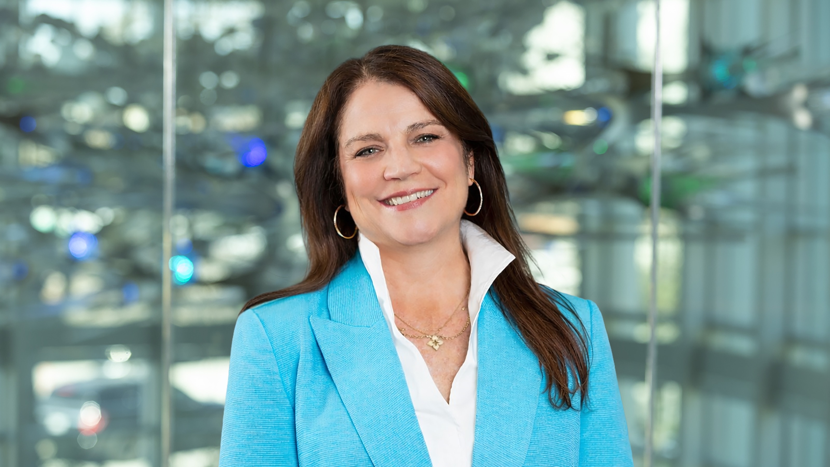 Headshot of Cecilia Perez Verdia against a backdrop of glass neuron sculptures at Center for BrainHealth in Dallas, Texas.