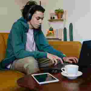 Young adult wearing a headset and working on a laptop.