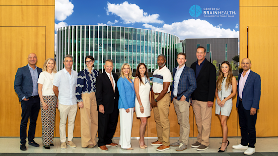 A group of eleven new board members posing in front of a Center for BrainHealth New Board Orientation banner.