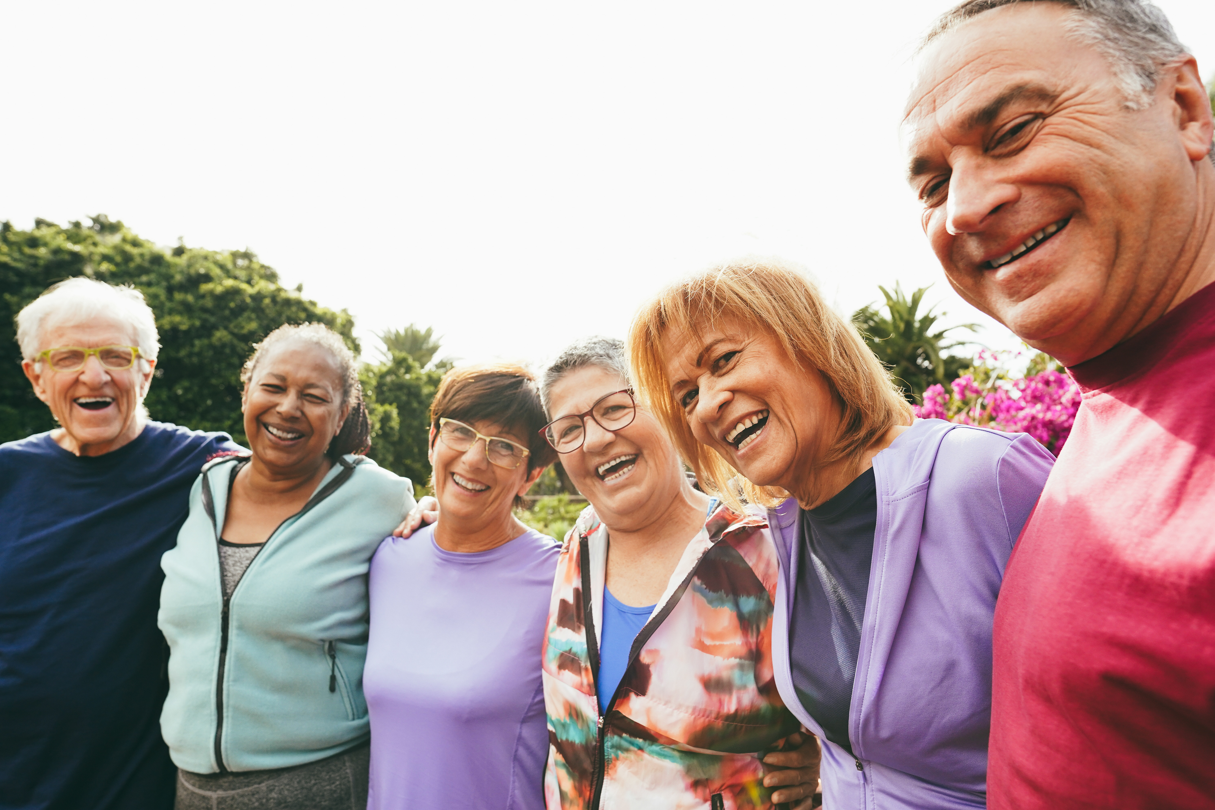A diverse group of mature friends huddle together for a candid group photo. 