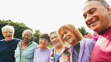 A diverse group of mature friends huddle together for a candid group photo.