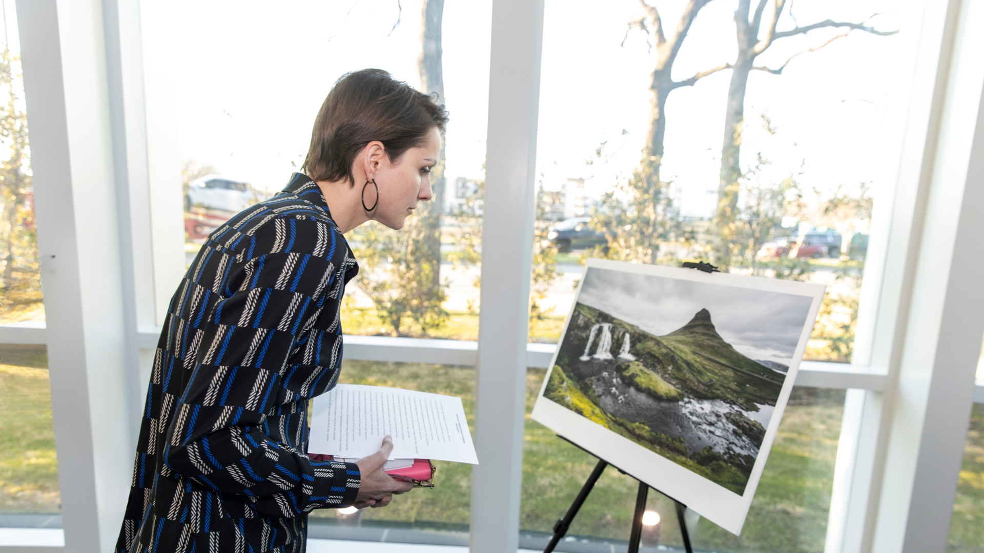 A young woman leans in to examine a landscape photo on an easel near large windows, inside Center for BrainHealth's Brain Performance Institute in Dallas, Texas.