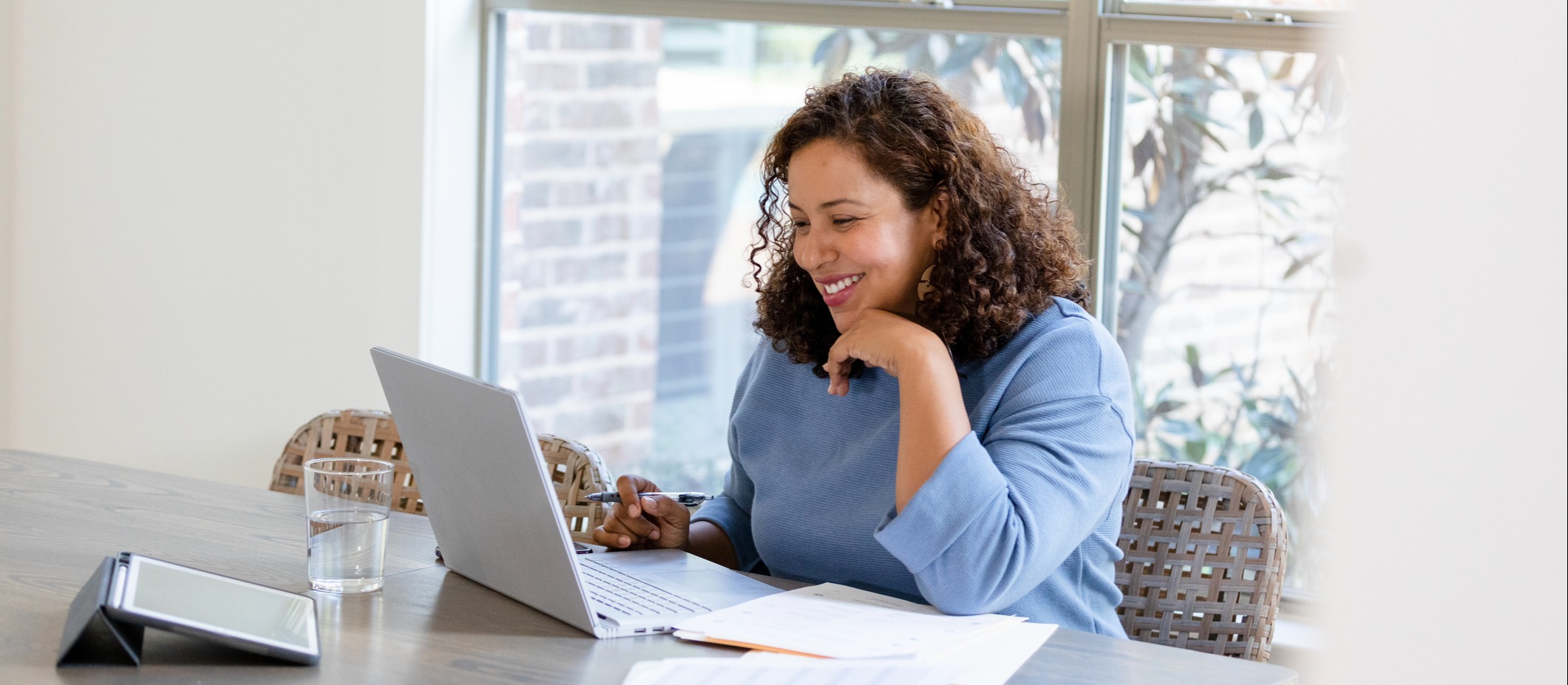 A smiling young woman engages in online SMART training on her home computer. 