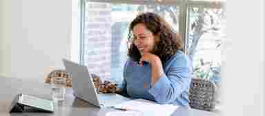 A smiling young woman engages in online SMART training on her home computer.