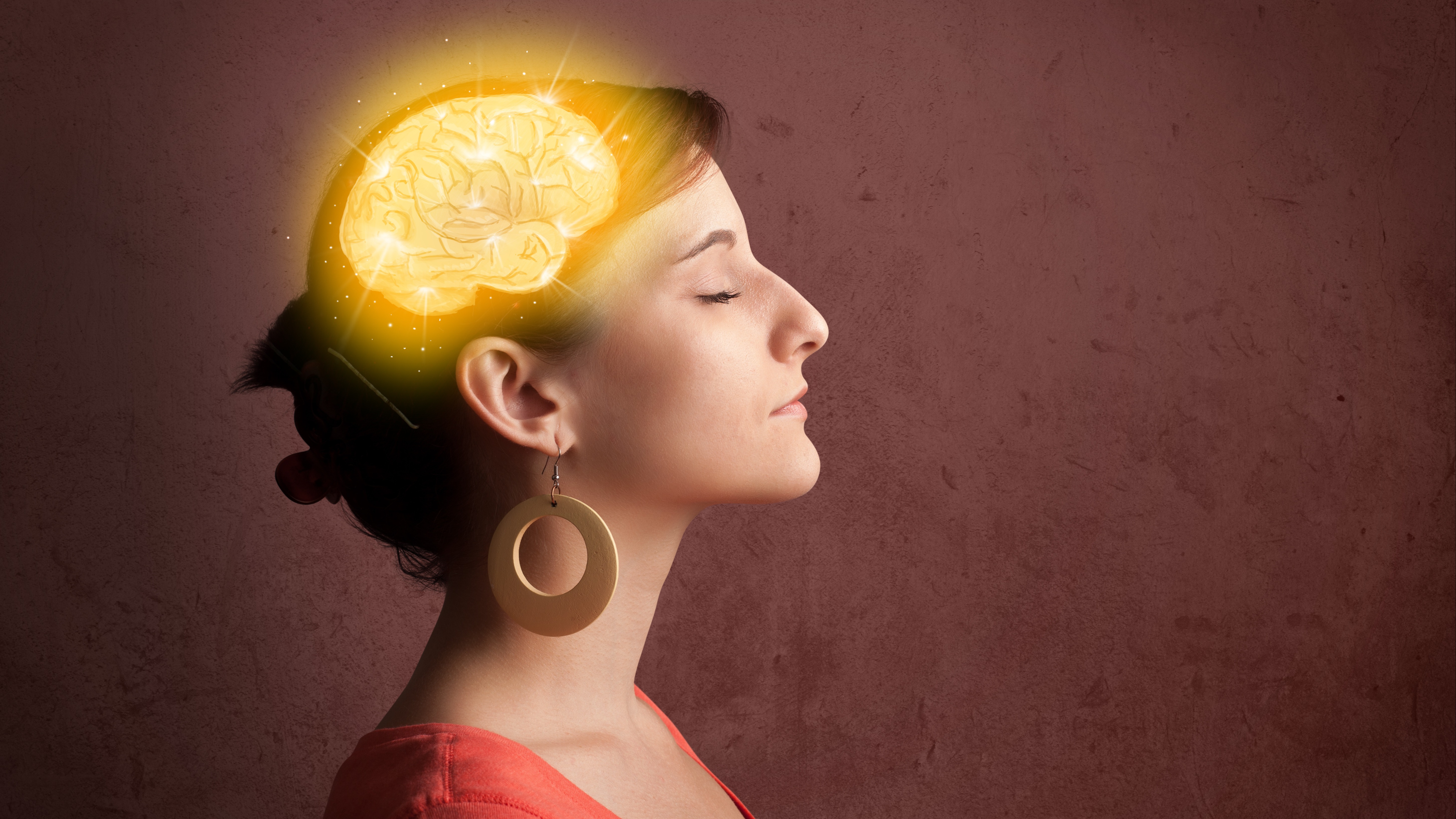 A woman with closed eyes and a glowing golden brain illustration overlaid on her head, symbolizing mindfulness or mental clarity.