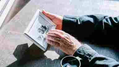 Two hands gently holding a framed photograph.